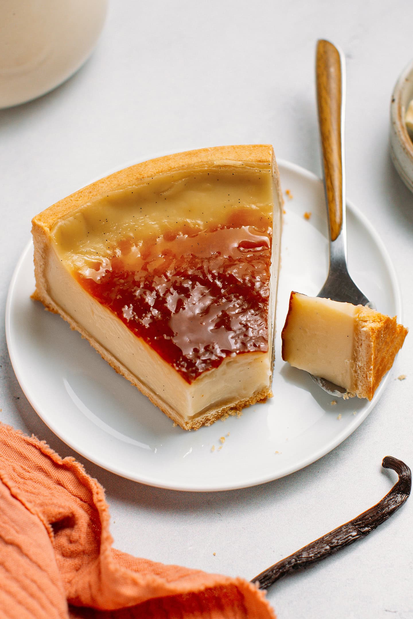 Slice of vegan custard tart with caramelized top on a small dessert plate.