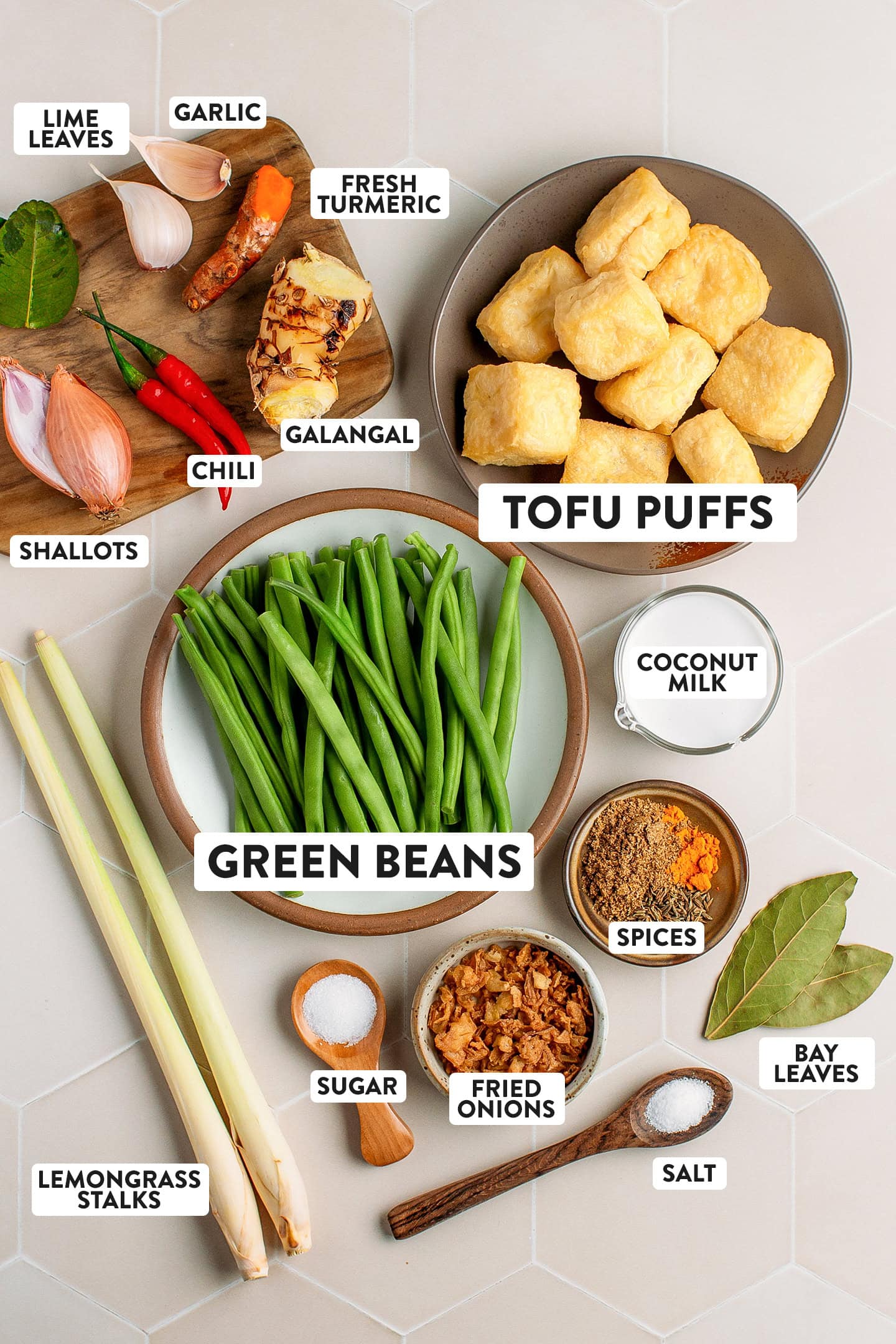 Ingredients like green beans, tofu puffs, galangal, coconut milk, spices, and shallots.