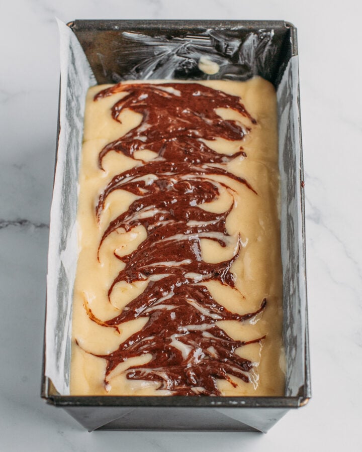 Unbaked marble cake in a loaf pan.