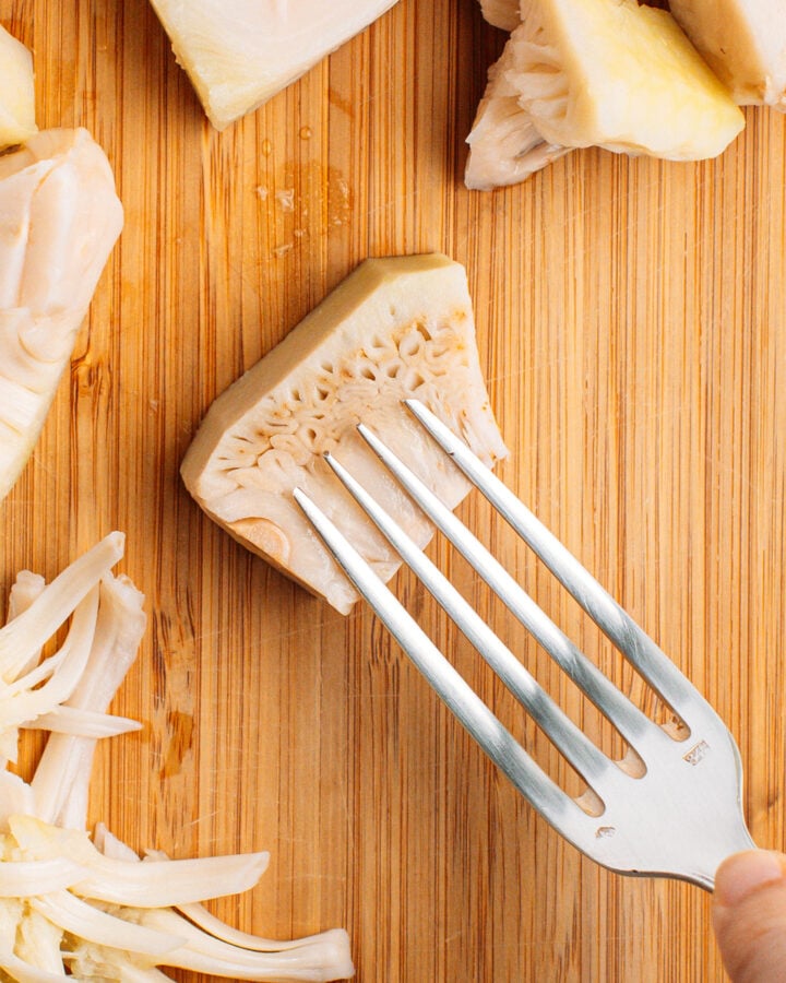 Holding a fork over a piece of jackfruit.