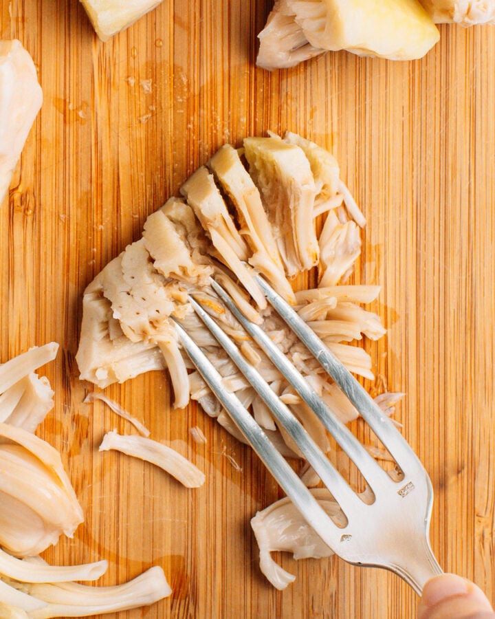 Mashing a piece of jackfruit using a fork.