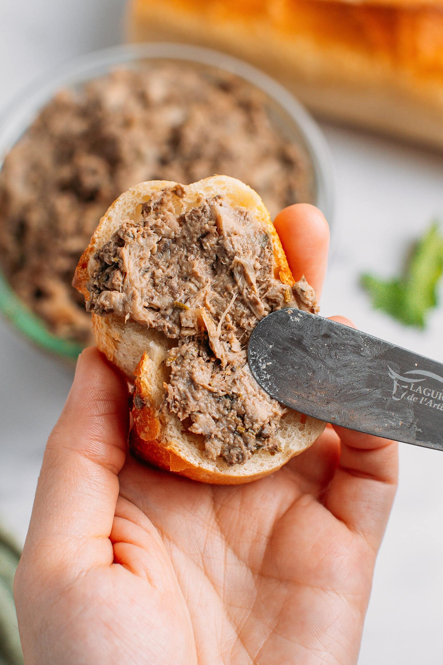 Spreading vegan rillettes on a slice of toasted bread.