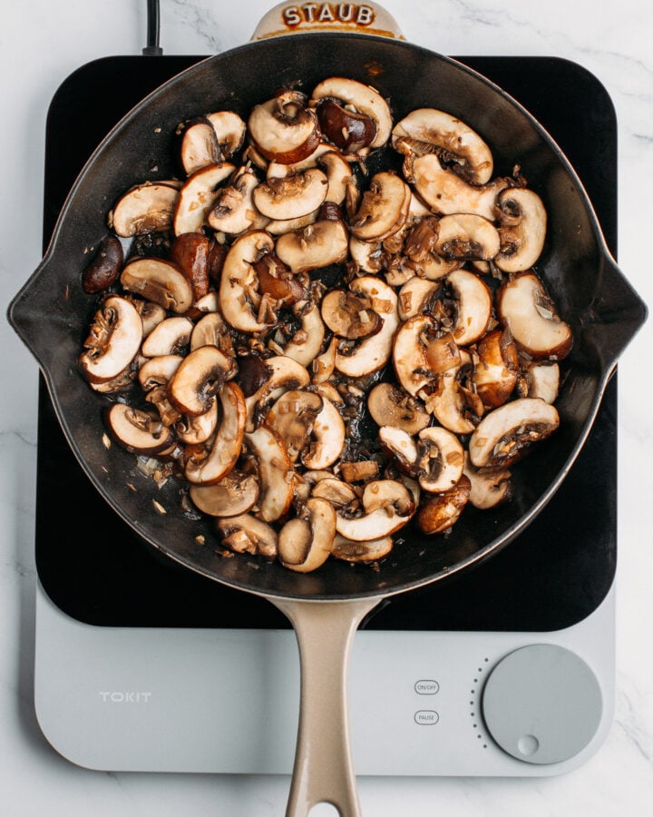 Sautéed sliced mushrooms in a skillet.