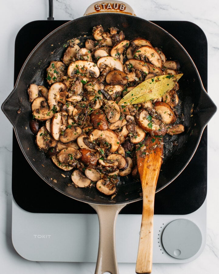 Sautéed mushrooms tossed with dried herbs in a skillet.