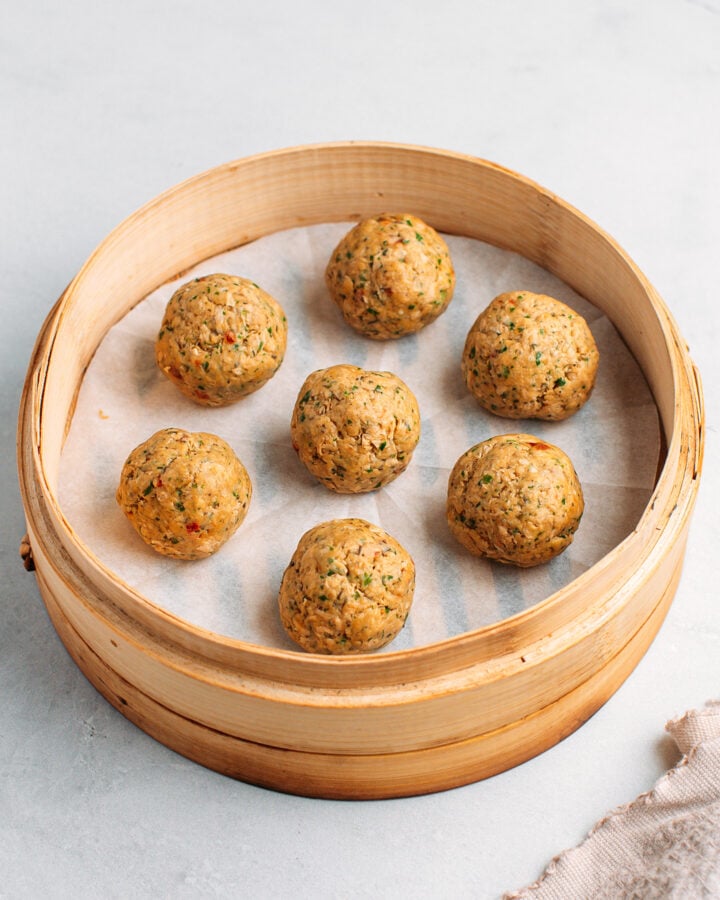 Uncooked vegan meatballs in a bamboo basket steamer.