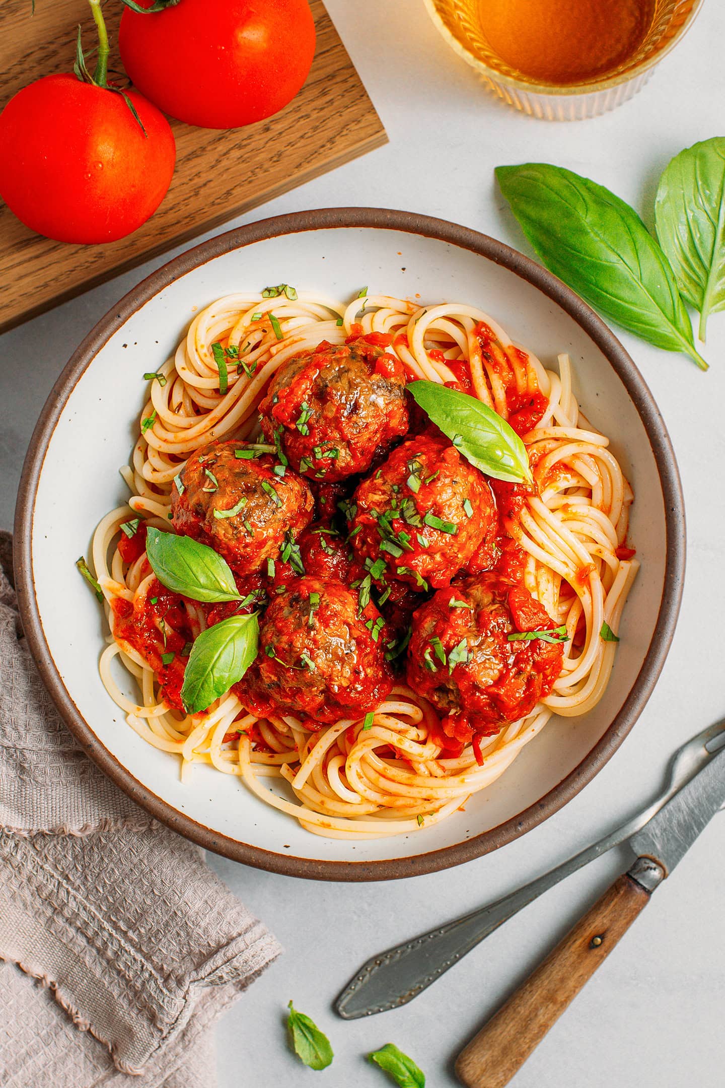 Plate filled with spaghetti, tomato sauce, meatballs, and garnished with fresh basil.