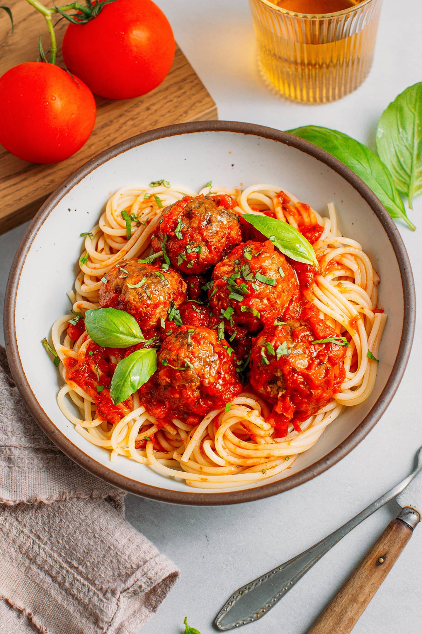 Plate filled with spaghetti, tomato sauce, vegan meatballs, and chopped basil.