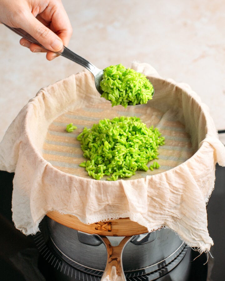 Filling a bamboo basket steamer with pandan sticky rice.