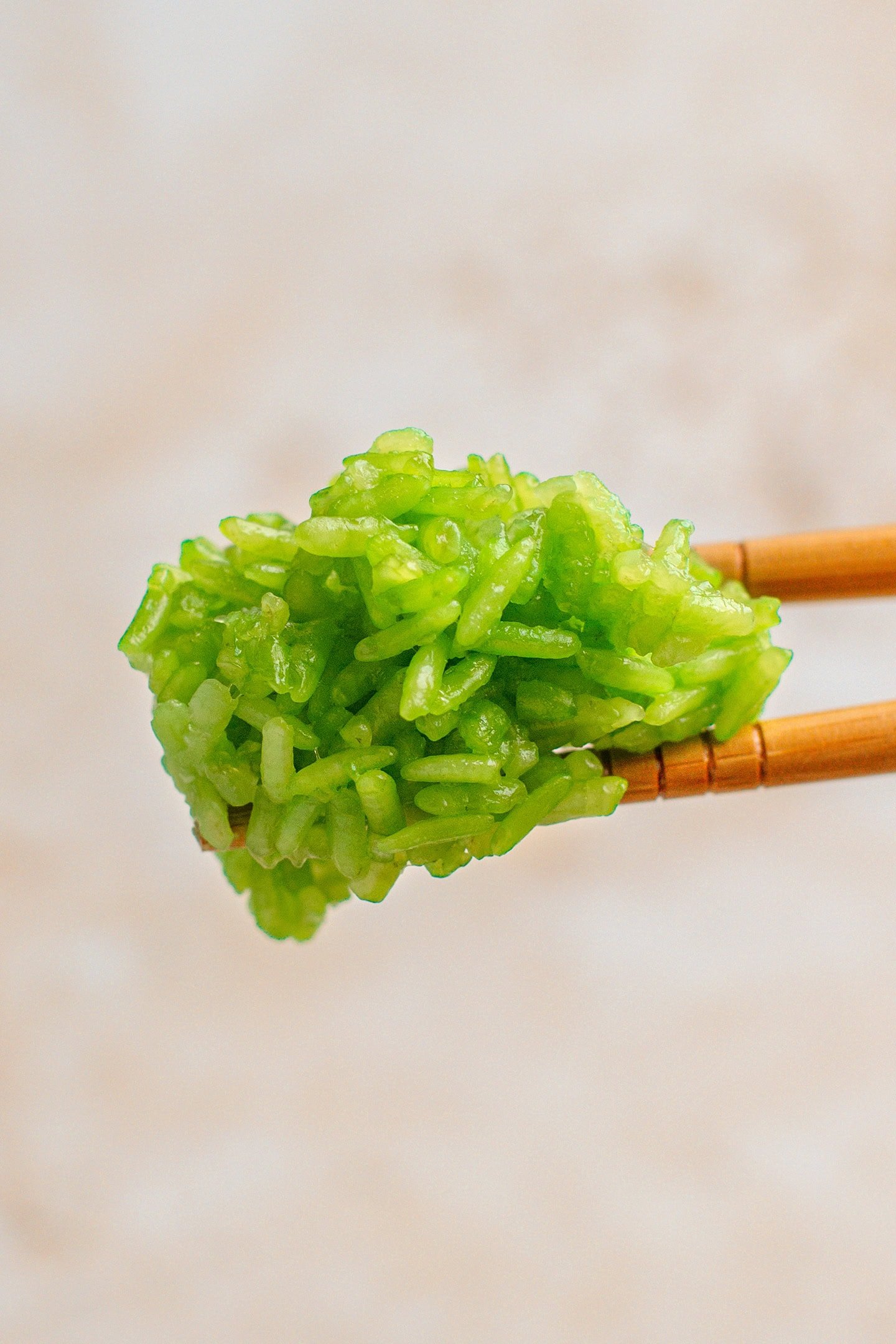Close-up of a pair of chopsticks holding some pandan sticky rice.