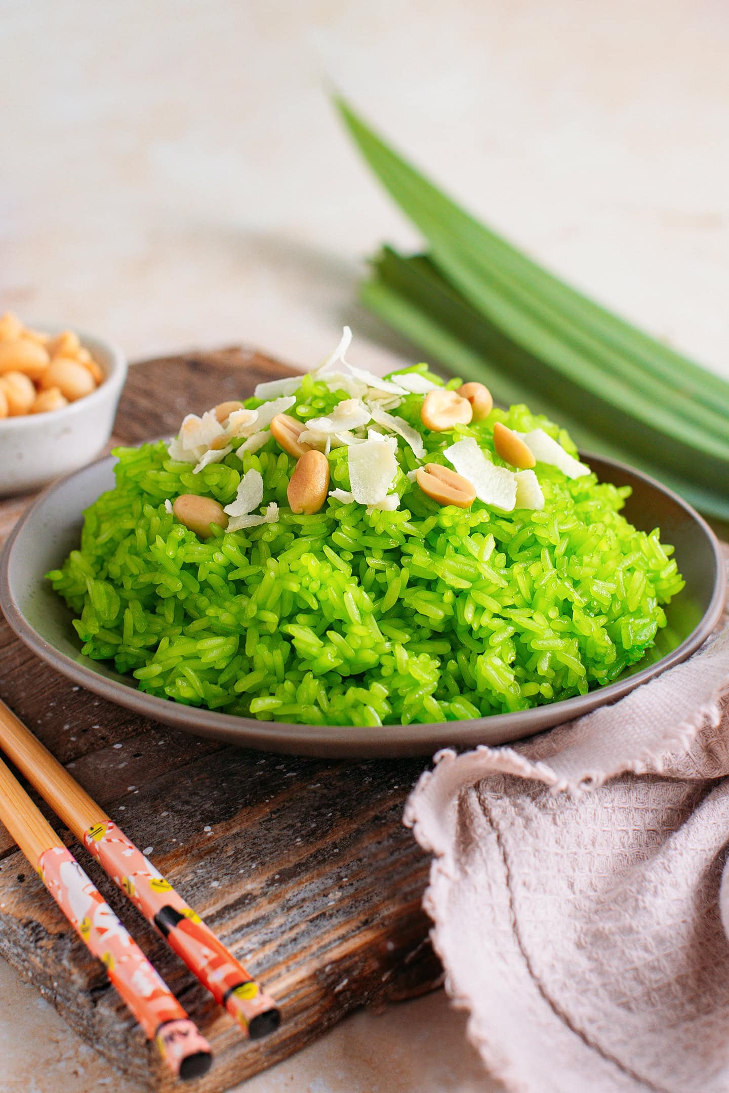Pandan sticky rice topped with peanuts and coconut flakes on a small plate.