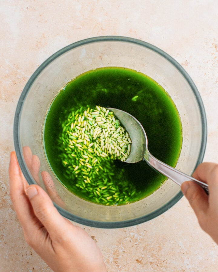Stirring rice with pandan juice in a small bowl.