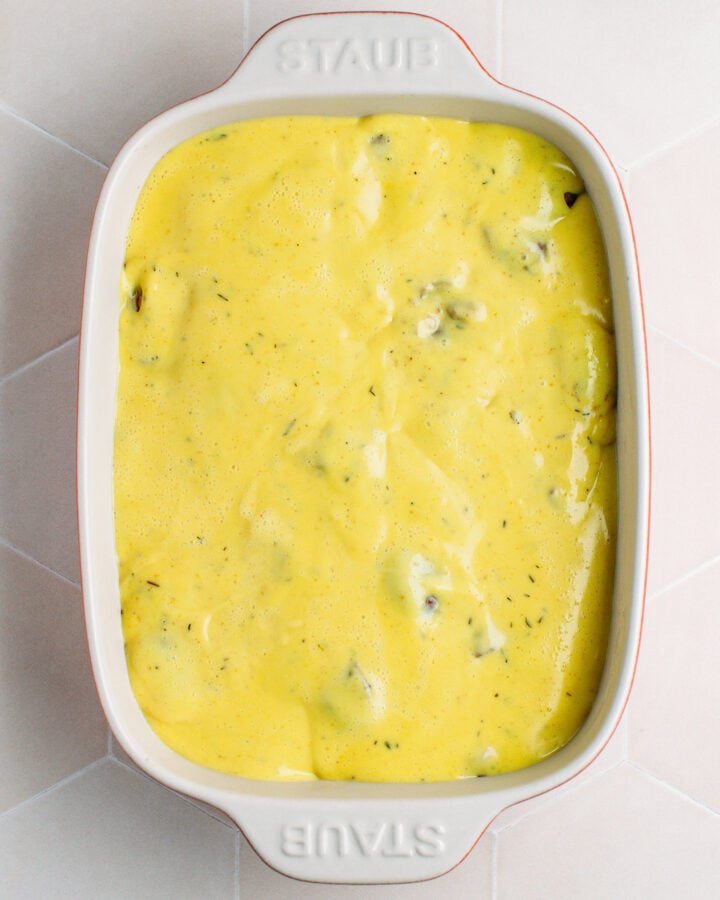 Vegan cream poured over parsnips, carrots, and chestnuts in a baking dish.
