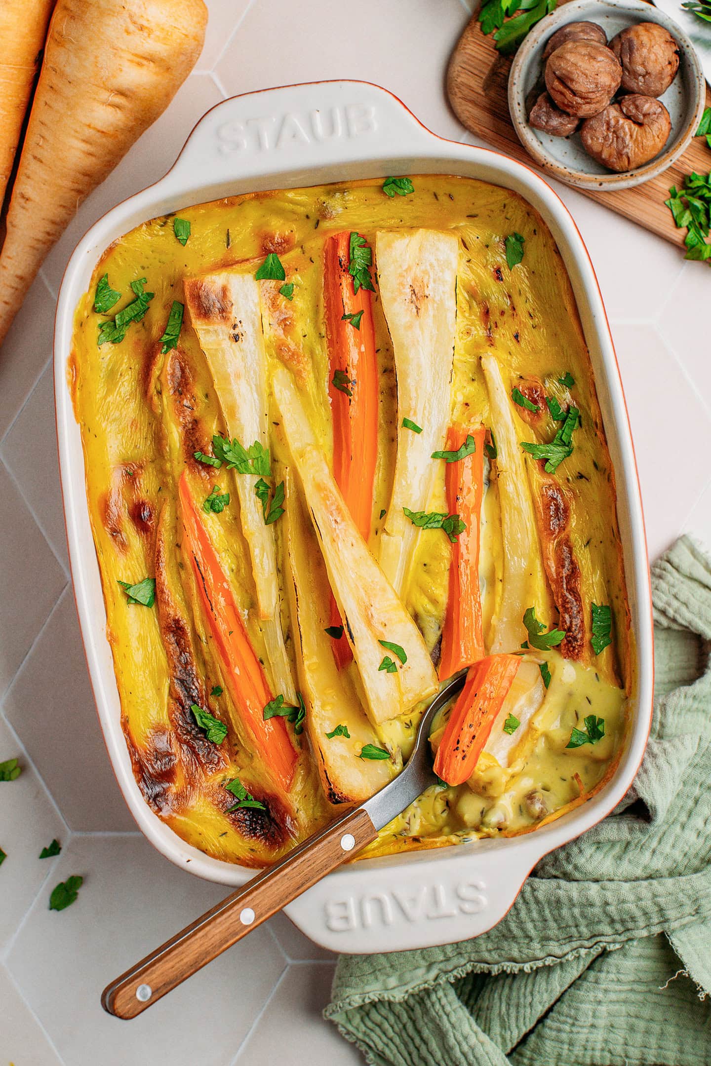 Casserole filled with parsnips and carrots and topped with chopped parsley.