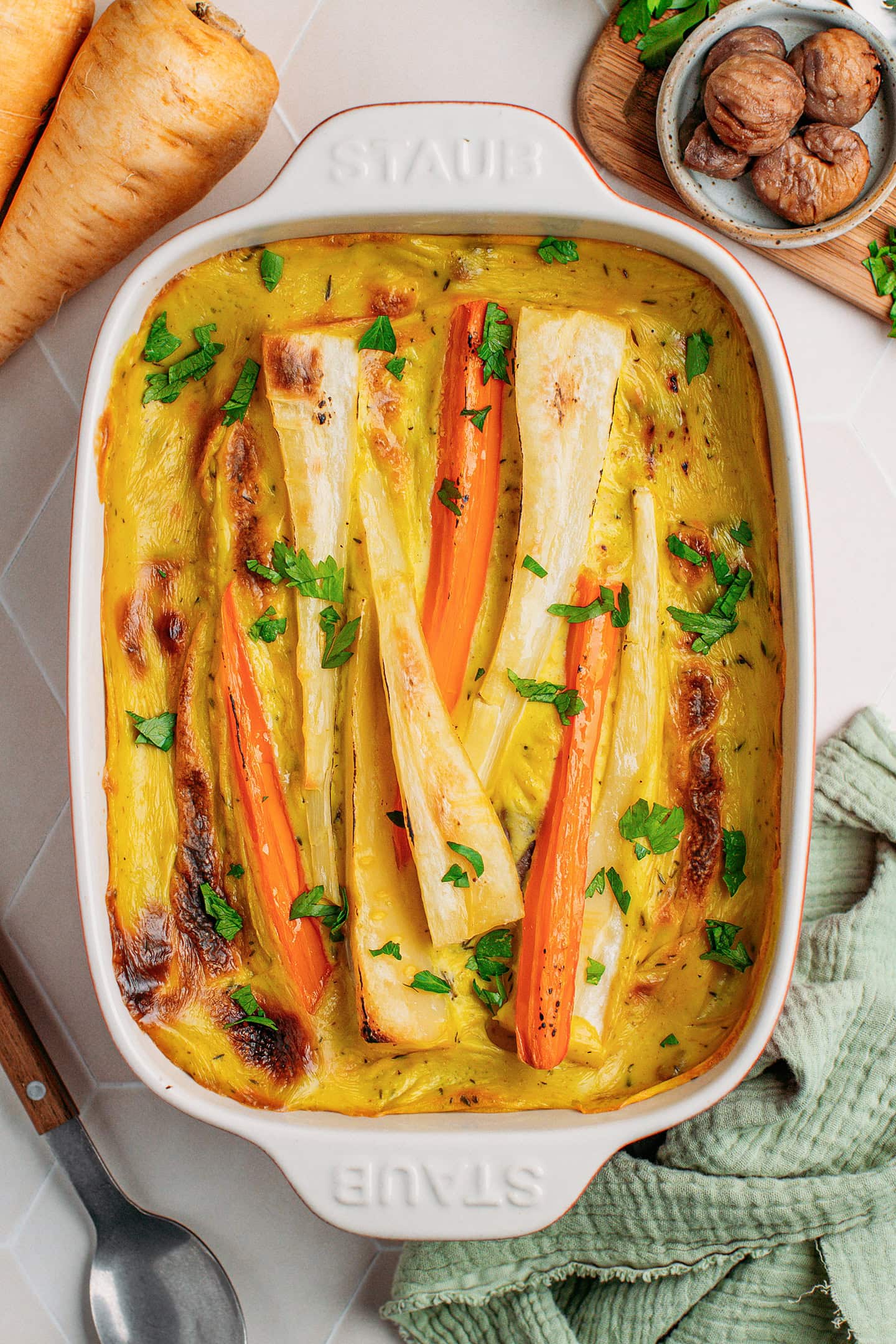 Parsnip and carrot casserole topped with chopped parsley.
