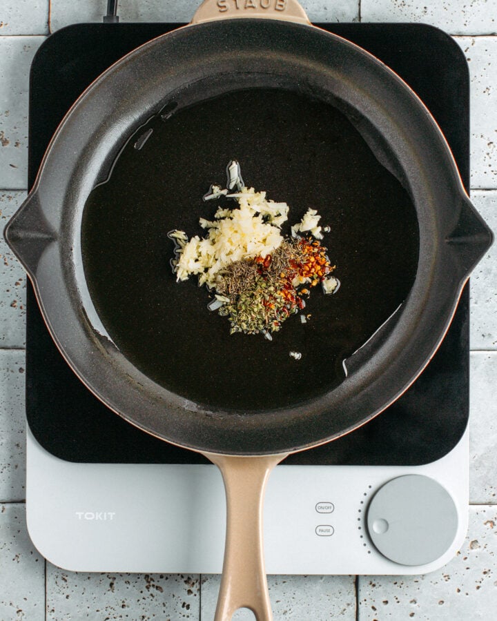 Minced garlic and dried herbs in a skillet.