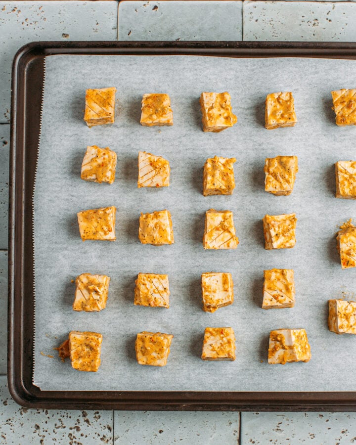 Marinated tofu cubes on a baking sheet.