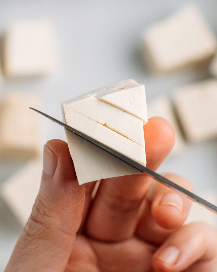 Slicing thin openings on a cube of tofu.