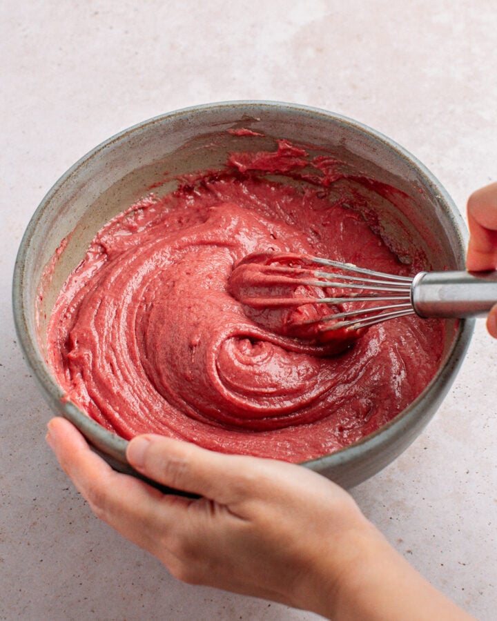 Whisking strawberry cake batter in a bowl.