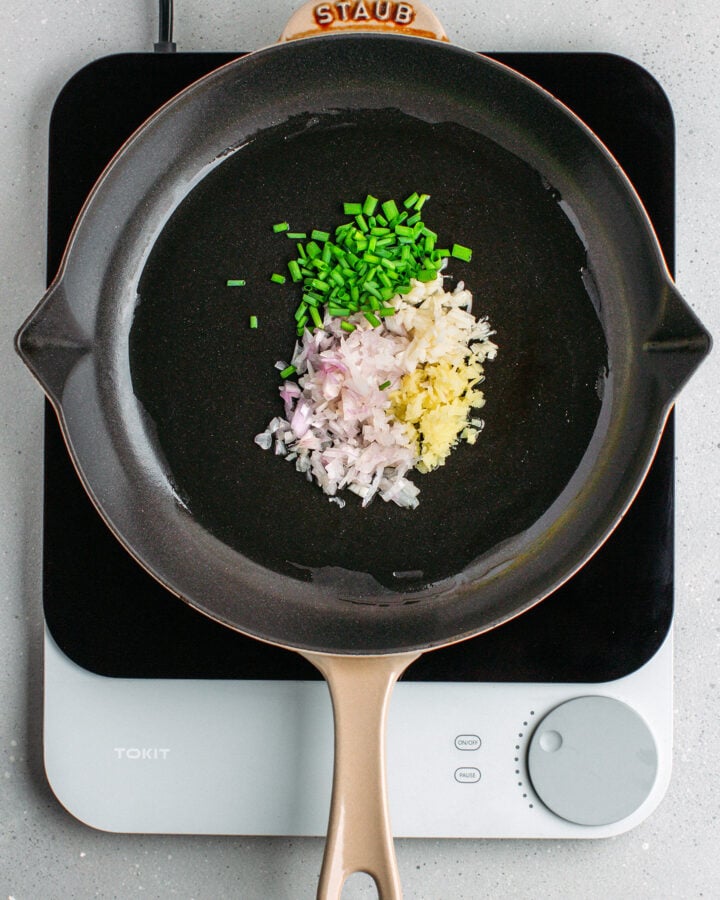 Chopped green onions, shallots, ginger, and garlic in a skillet.