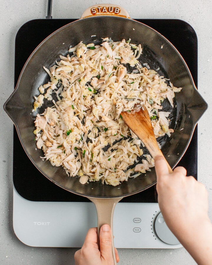 Stirring shredded jackfruit in a skillet.