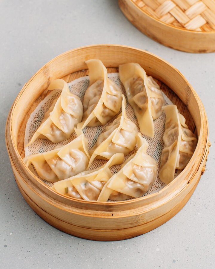 Steamed dumplings in a bamboo basket steamer.