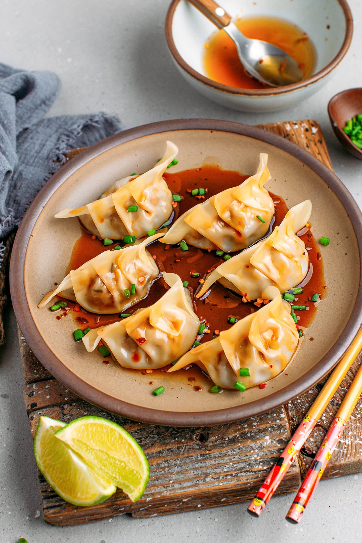 Six jackfruit dumplings topped with chopped scallions on a brown plate.