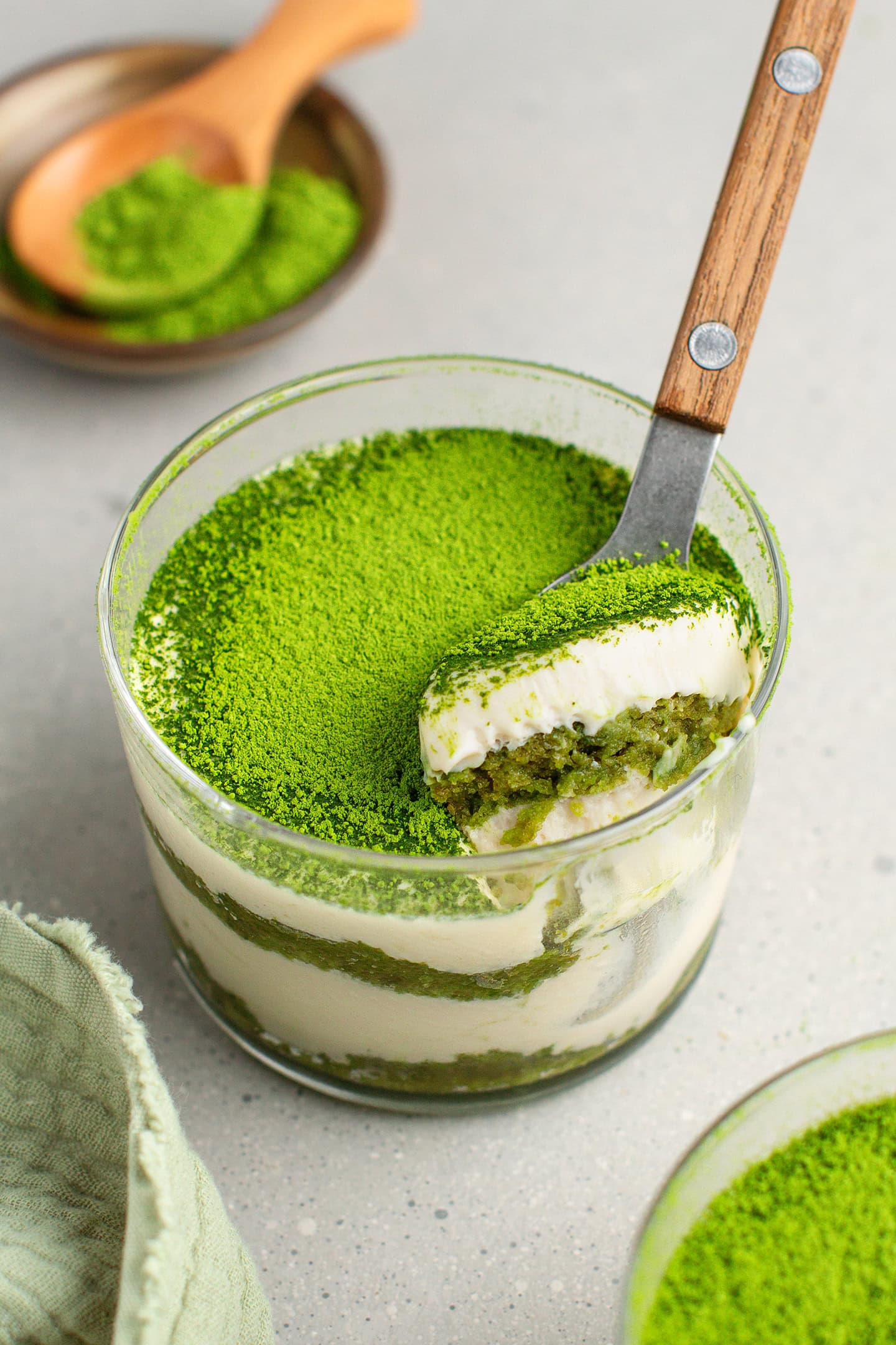 Digging a spoon into a ramekin of matcha tiramisu.
