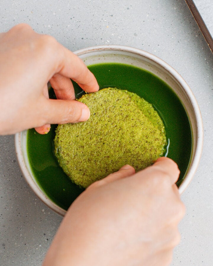 Dipping a round of sponge cake into matcha.