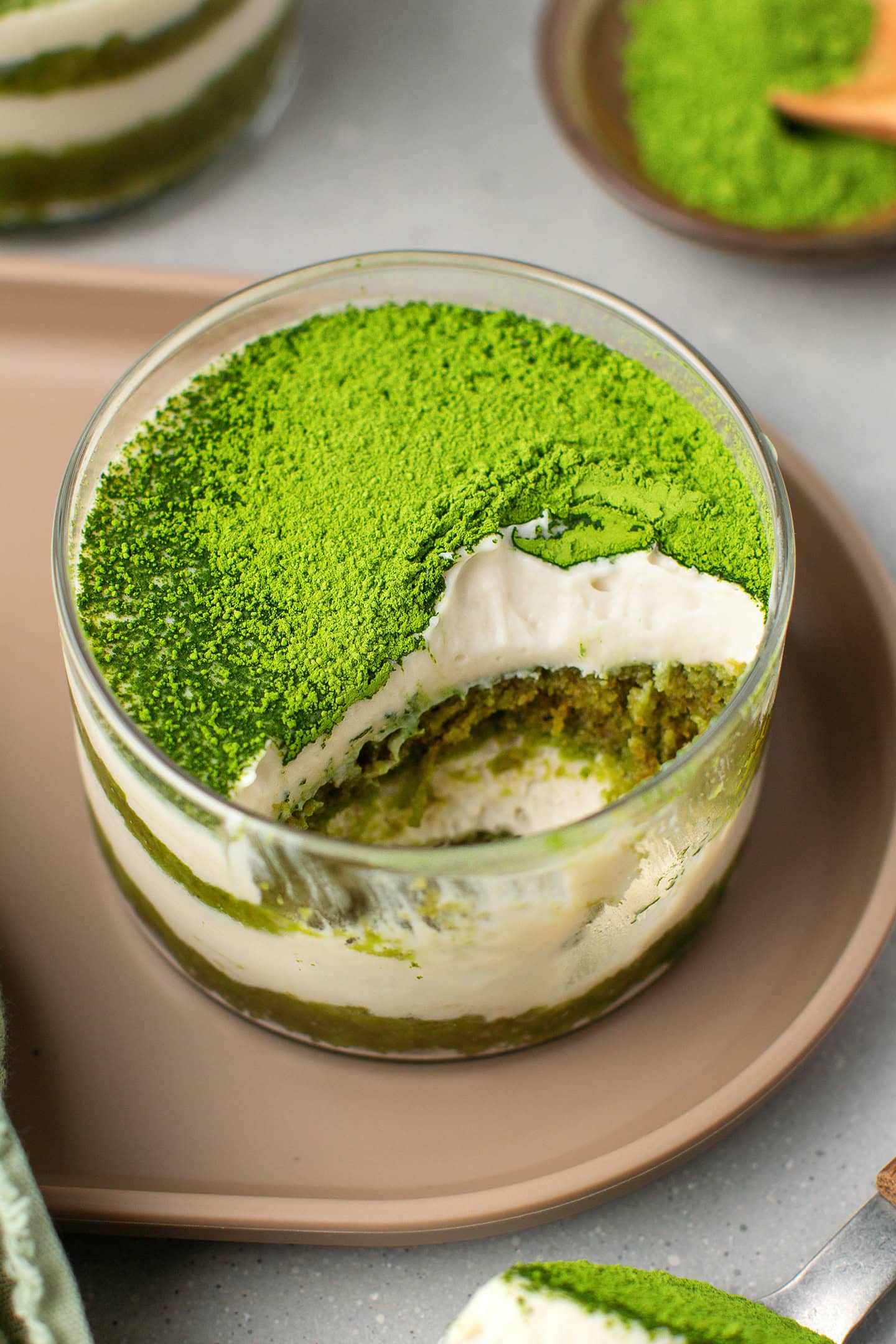 Matcha tiramisu in a ramekin with layers of sponge cake and vanilla cream.