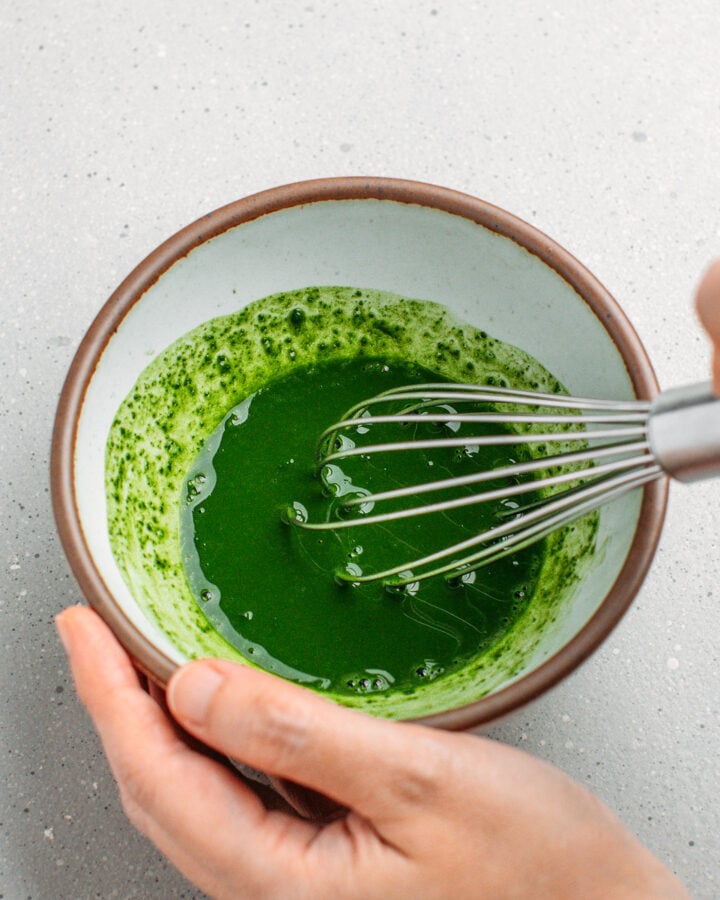 Whisking matcha powder in hot water.