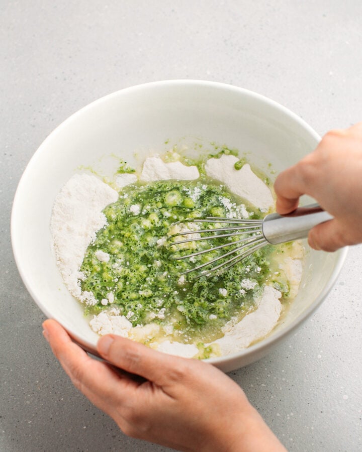 Whisking matcha, oil, milk, flour and sugar in a mixing bowl.