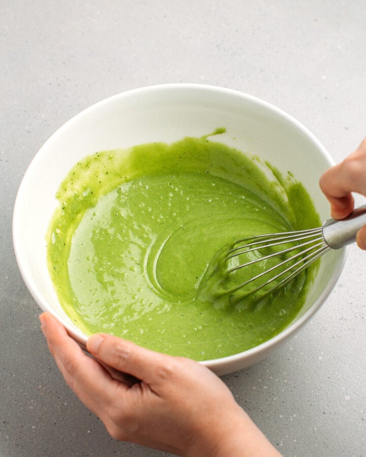 Whisking matcha sponge cake batter in a mixing bowl.