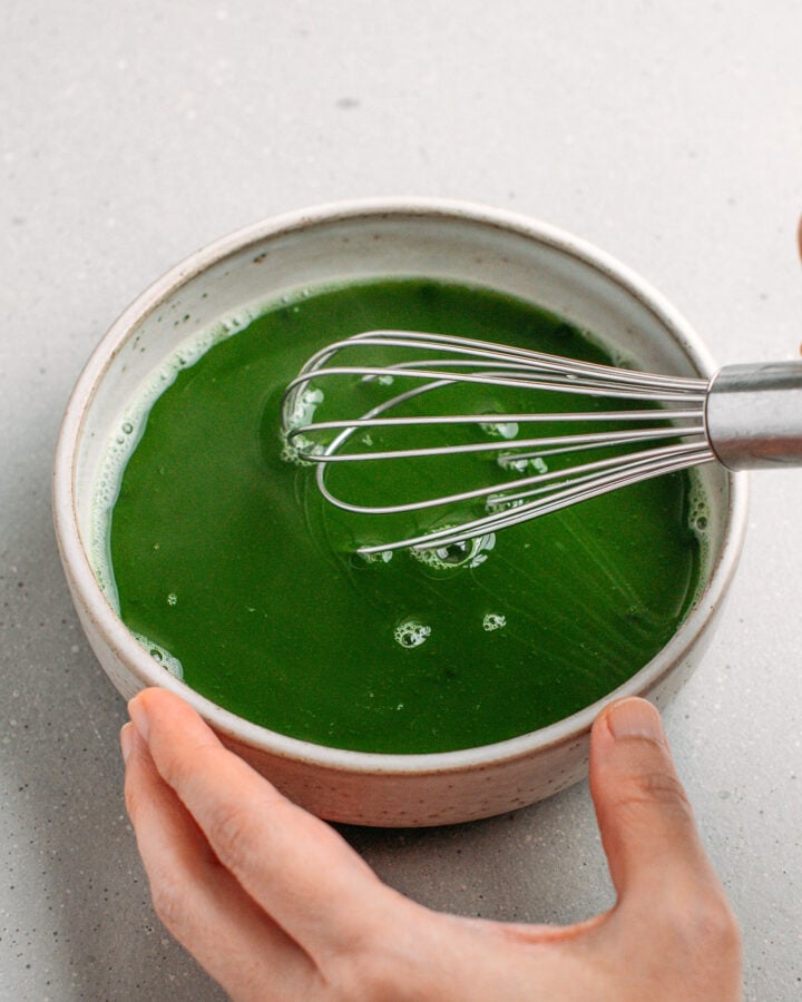 Whisking matcha with water in a small bowl.