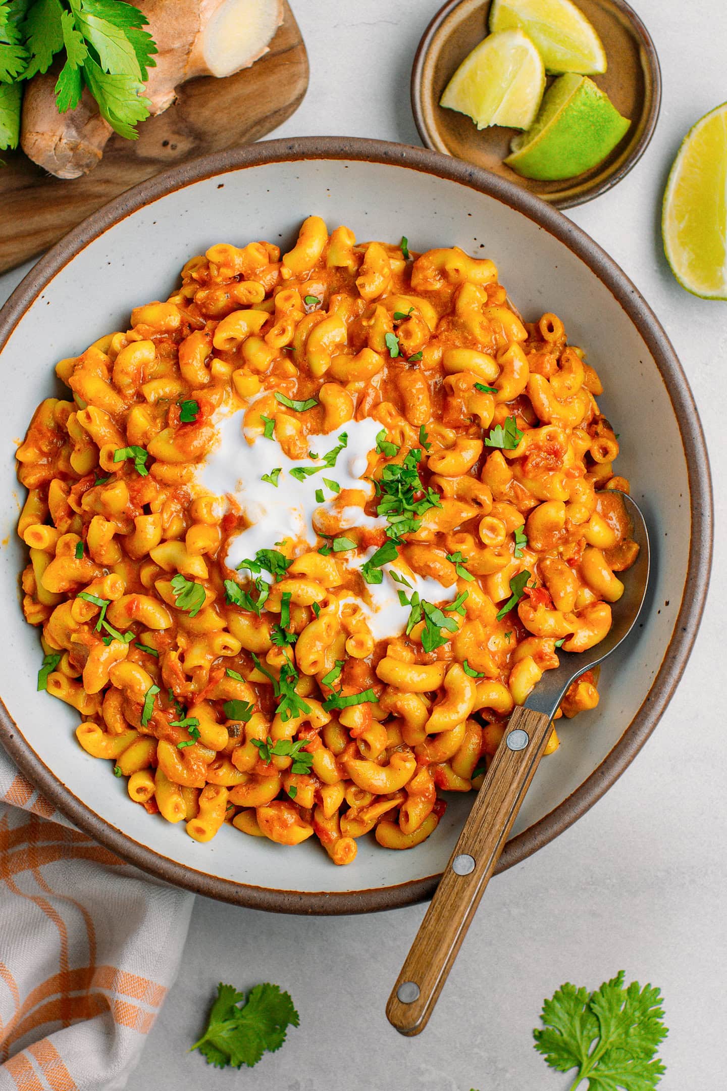 Creamy macaroni dish with tikka masala sauce, coconut cream, and chopped parsley in a bowl.
