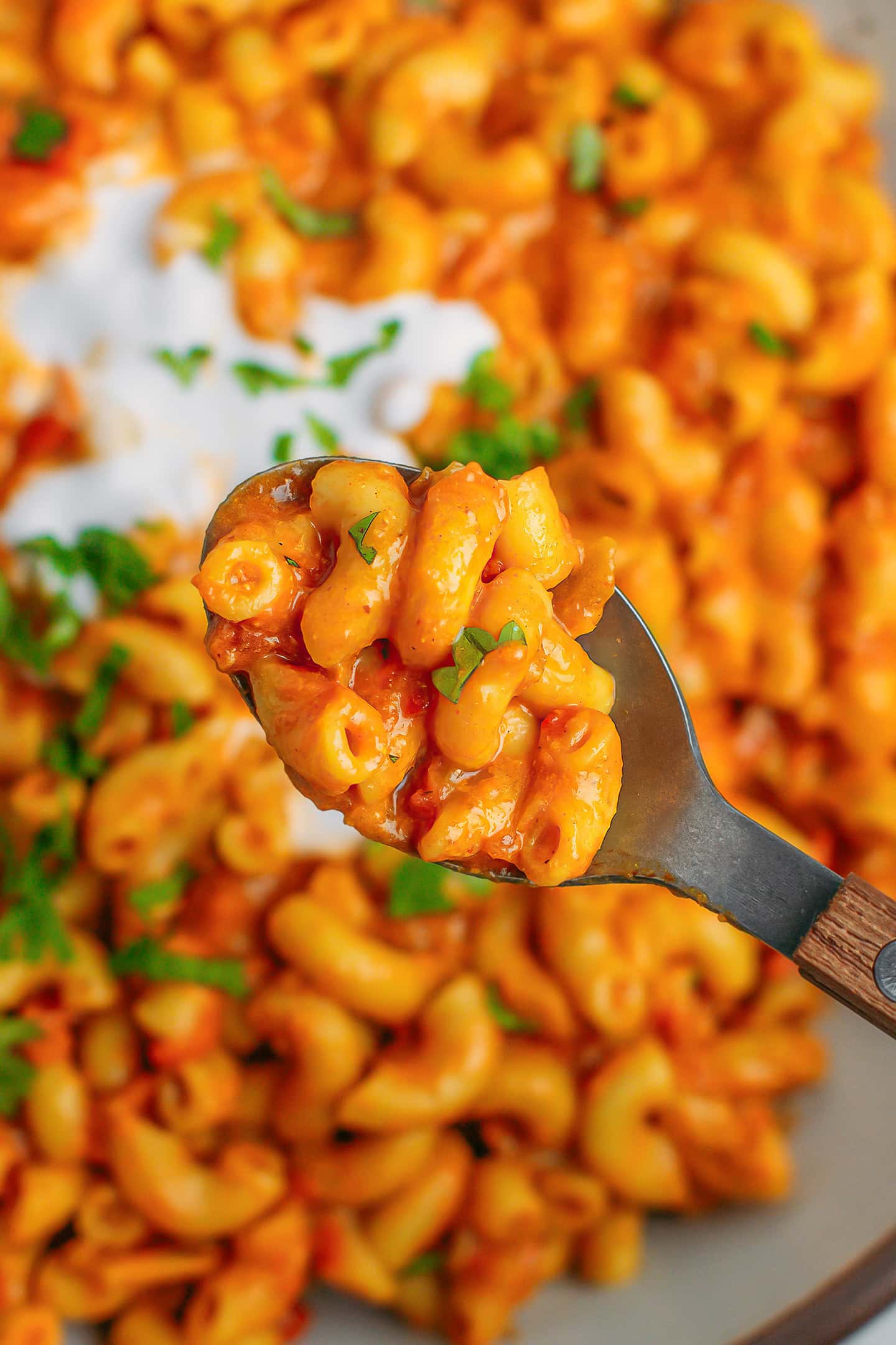 Close-up of a spoonful of macaroni cooked in a tikka masala sauce.
