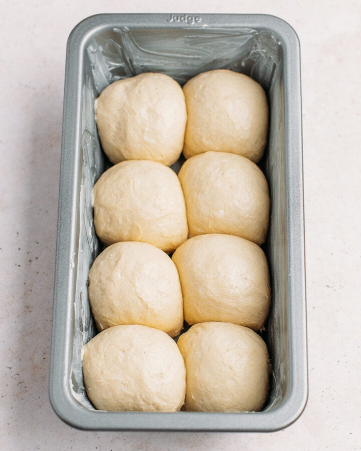 Fluffy dough balls in a baking pan, ready for proofing.