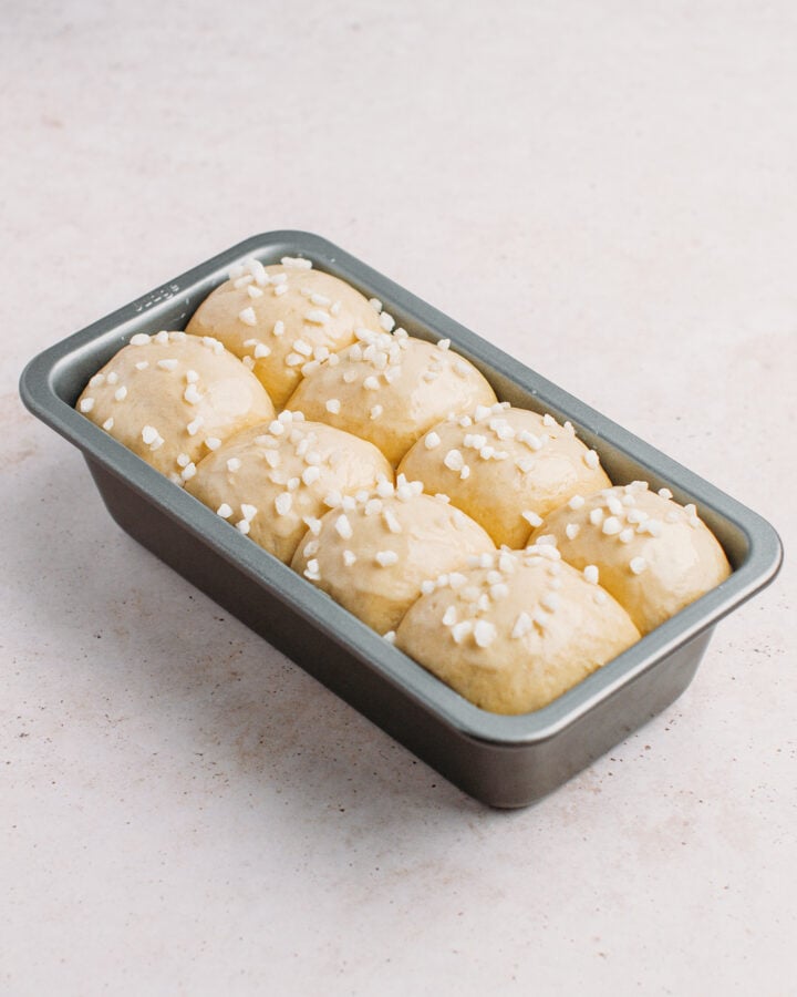 Brioche dough balls with pearl sugar in a baking dish.