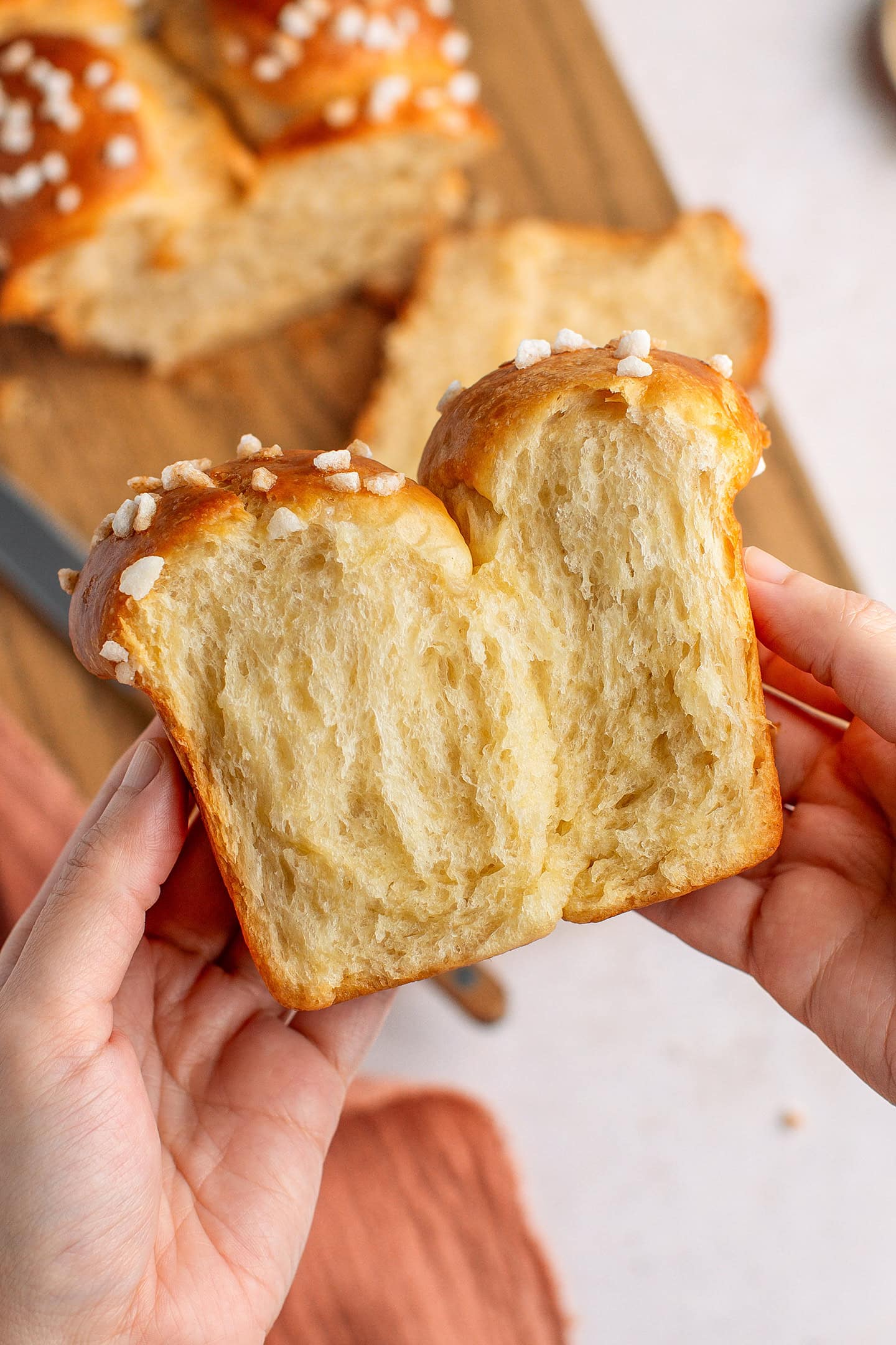 Holding a slice of stringy vegan brioche topped with pearl sugar.