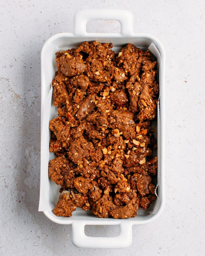 Protein bar mixture in a baking dish lined with parchment paper.