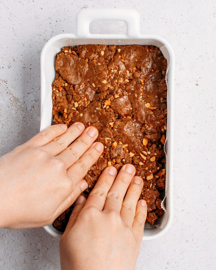 Pressing protein bar mixture into a small rectangle baking dish.