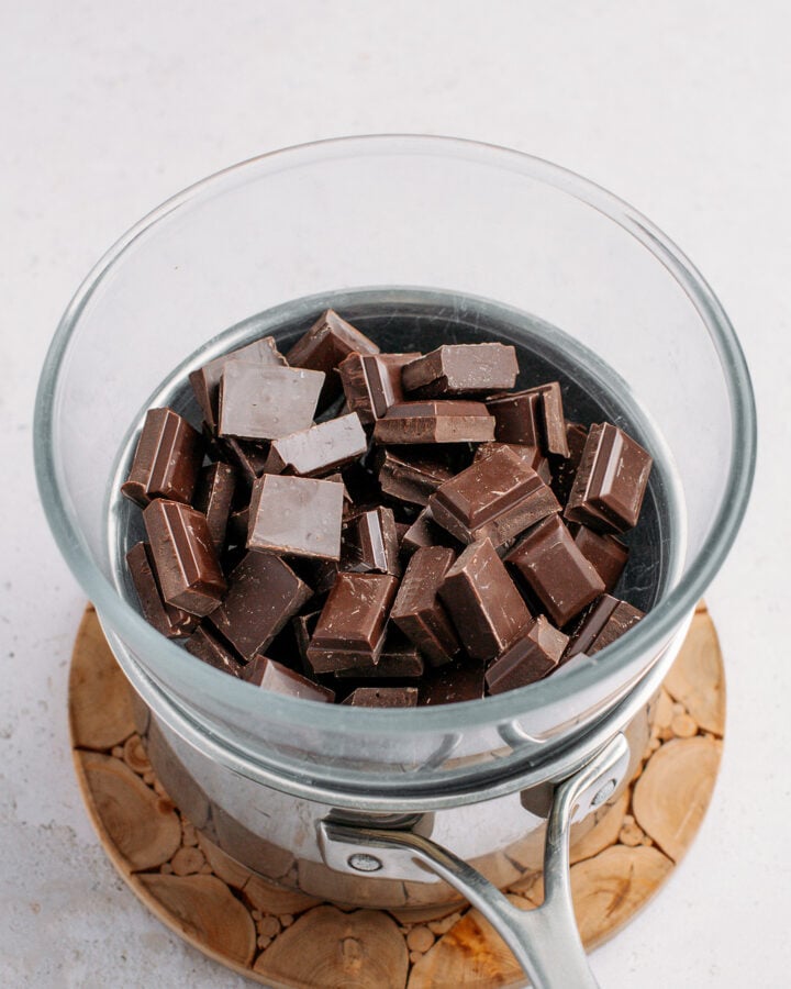 Dark chocolate chunks inside a bowl placed over a pot of hot water.