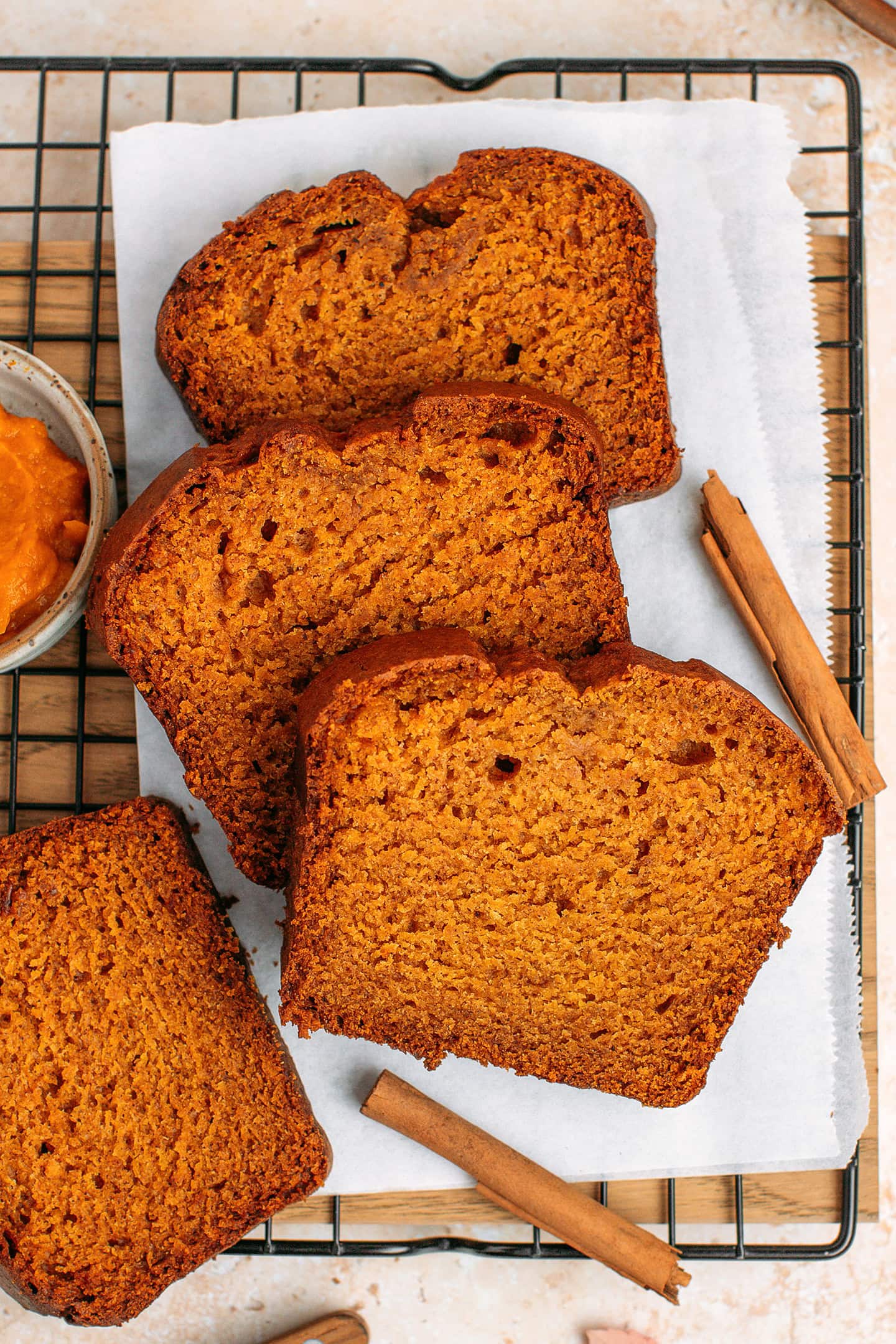 Four slices of pumpkin bread on a cooling rack.