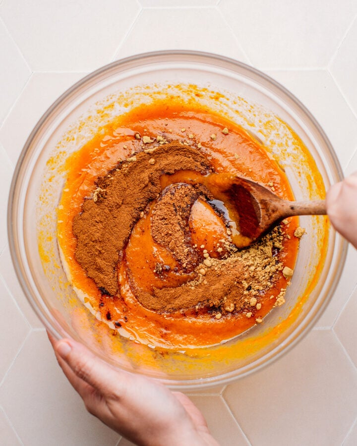 Mixing spices, pumpkin puree, and sugar in a mixing bowl.