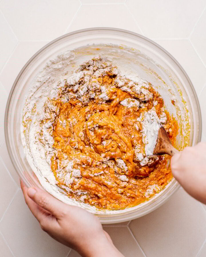 Mixing pumpkin purée, sugar, spices, and flour in a bowl.