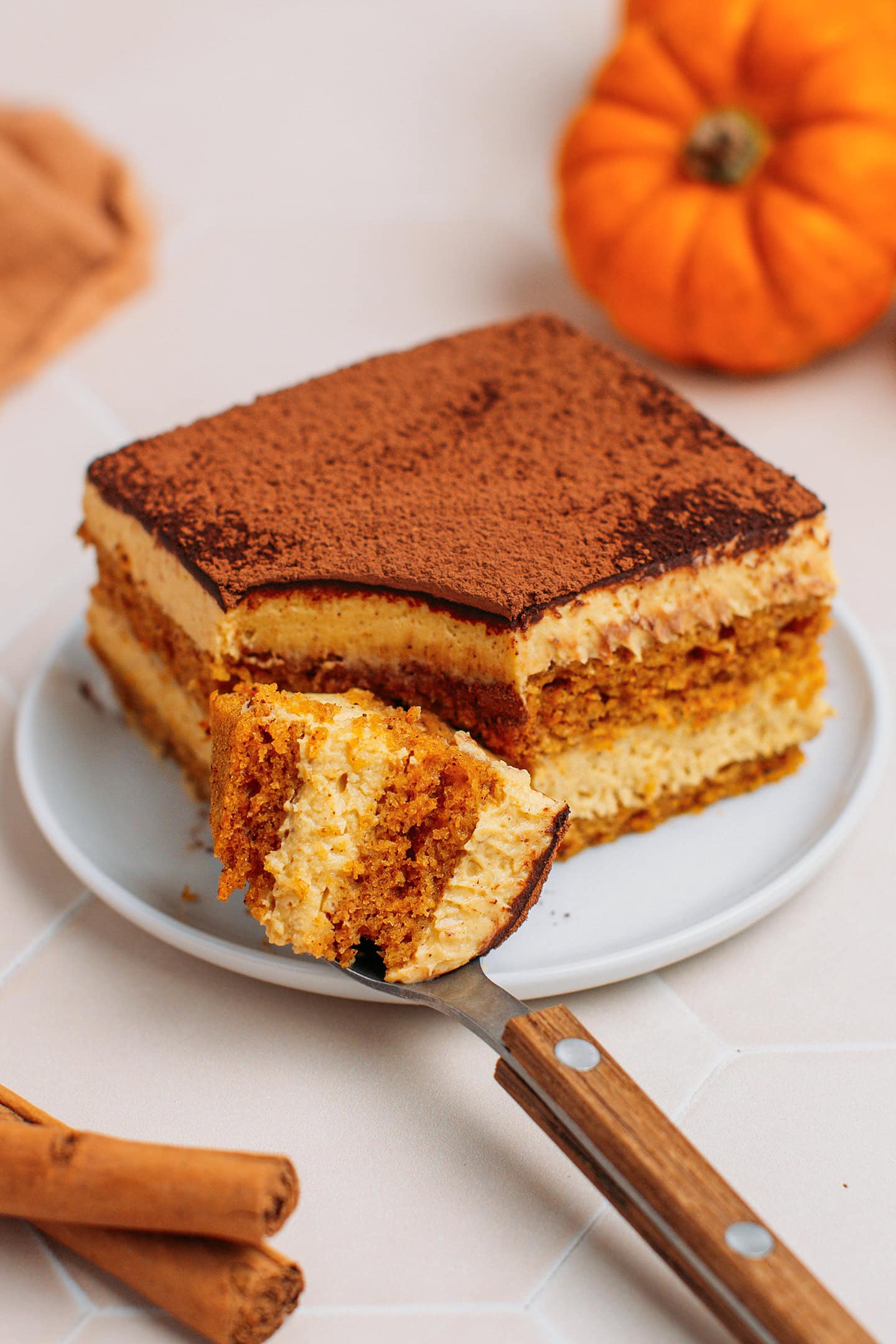 Spoonful and slice of pumpkin tiramisu on a white plate.