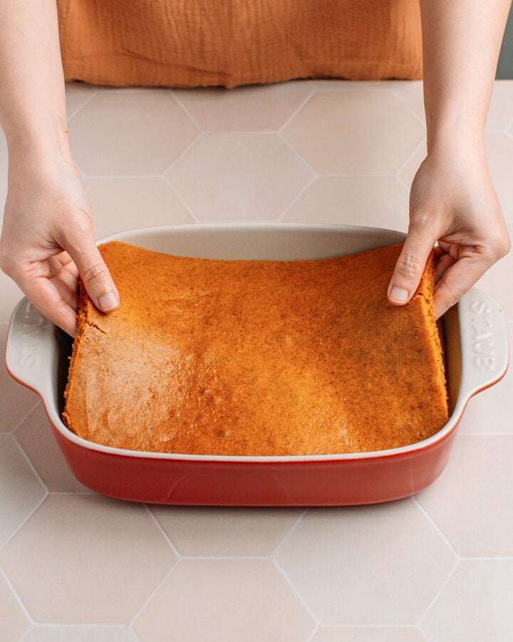Arranging a layer of pumpkin sponge cake in a baking dish.