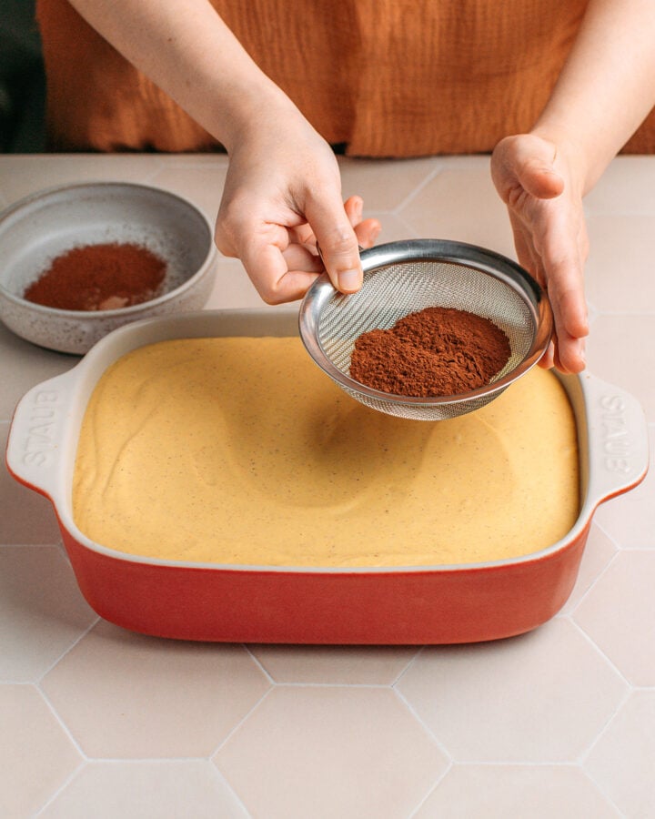 Dusting cocoa powder over pumpkin tiramisu.