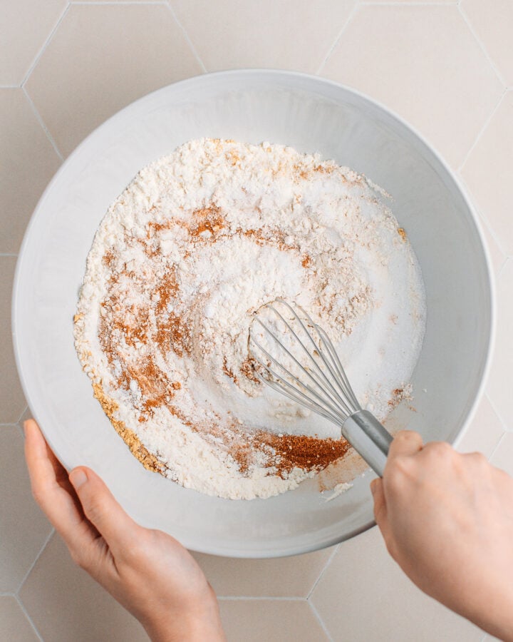 Whisking flour, sugar, and spices in a mixing bowl.