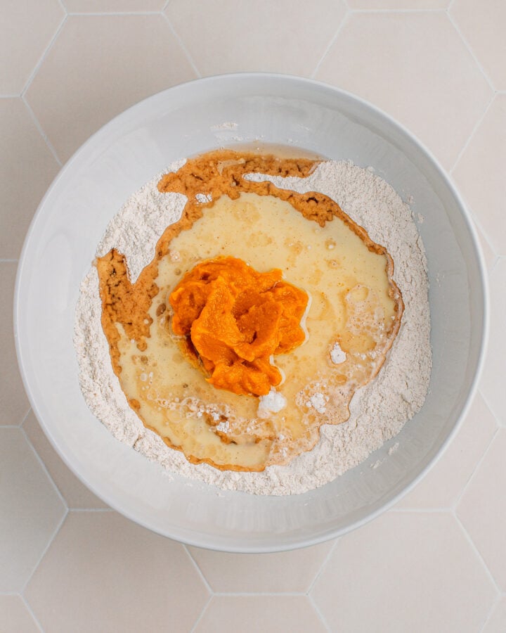 Flour, oil, pumpkin puree, and milk in a mixing bowl.