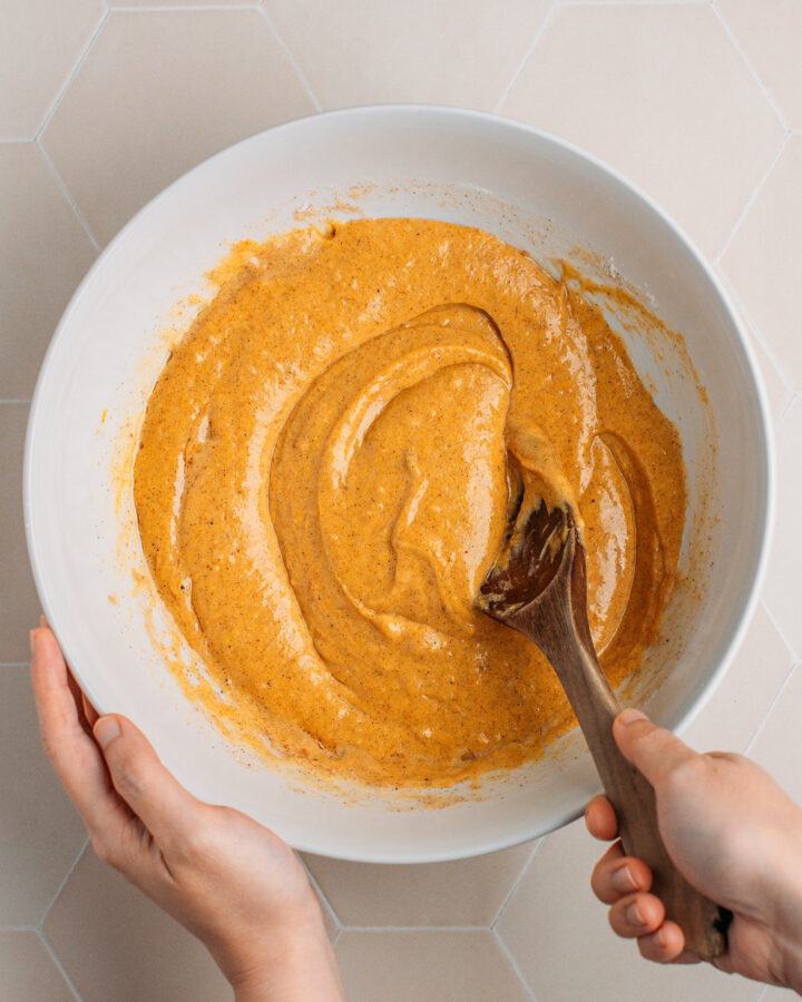 Mixing pumpkin sponge cake batter in a mixing bowl.
